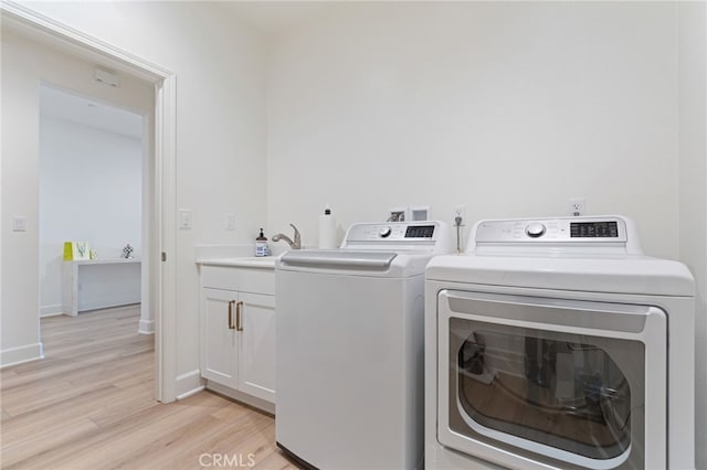 washroom featuring cabinets, independent washer and dryer, sink, and light hardwood / wood-style floors