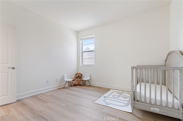 unfurnished bedroom featuring a nursery area and light hardwood / wood-style flooring