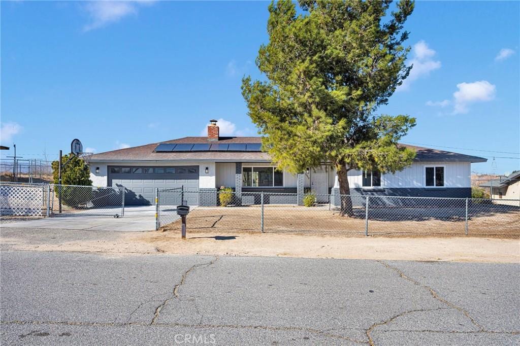 ranch-style house with a garage and solar panels