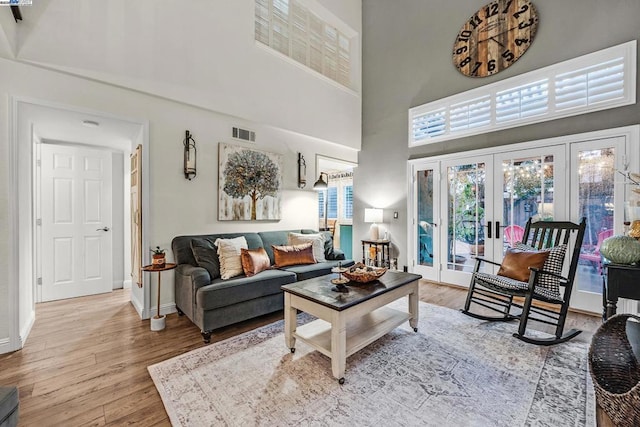 living room featuring french doors, a towering ceiling, and hardwood / wood-style floors