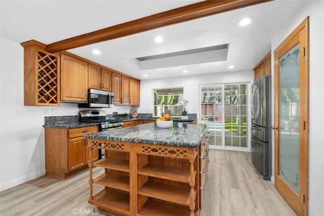 kitchen with dark stone countertops, light hardwood / wood-style floors, a center island, and appliances with stainless steel finishes