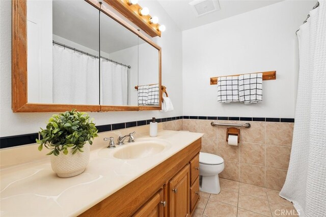 bathroom featuring tile patterned flooring, vanity, tile walls, and toilet