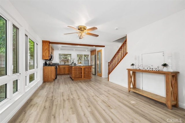 kitchen with light wood-type flooring, stainless steel refrigerator, kitchen peninsula, ceiling fan, and stove