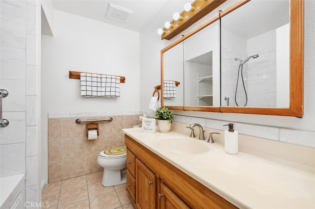 bathroom featuring tile walls, tiled shower, vanity, tile patterned floors, and toilet