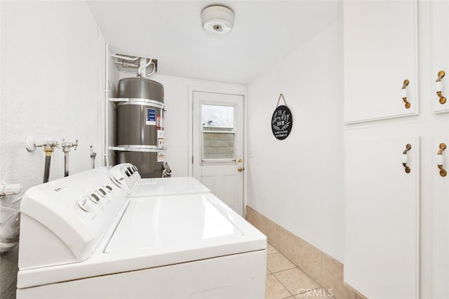 clothes washing area featuring cabinets, light tile patterned floors, independent washer and dryer, and strapped water heater