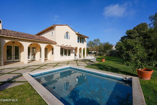 back of property with french doors, a patio, and a lawn