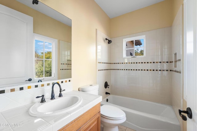 full bathroom featuring tiled shower / bath, vanity, and toilet