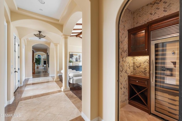 wine area featuring light tile patterned floors, decorative columns, and beverage cooler