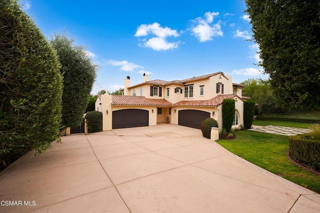 mediterranean / spanish home featuring a garage and a front lawn