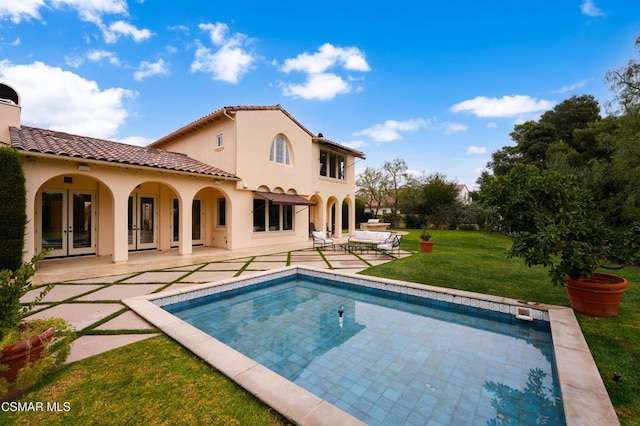 rear view of house featuring french doors, a patio area, and a lawn