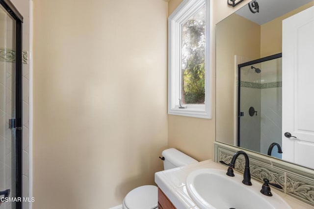 bathroom with toilet, vanity, and a shower with shower door