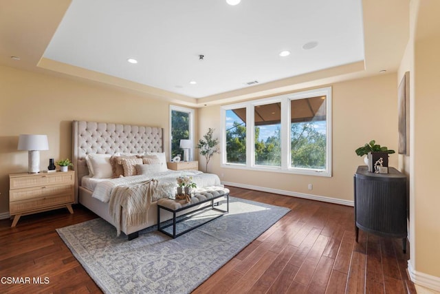 bedroom with dark hardwood / wood-style floors and a tray ceiling