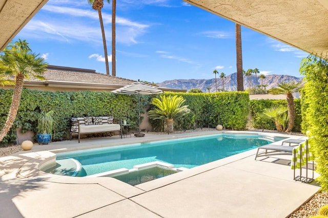 view of swimming pool with a patio, a mountain view, and an in ground hot tub