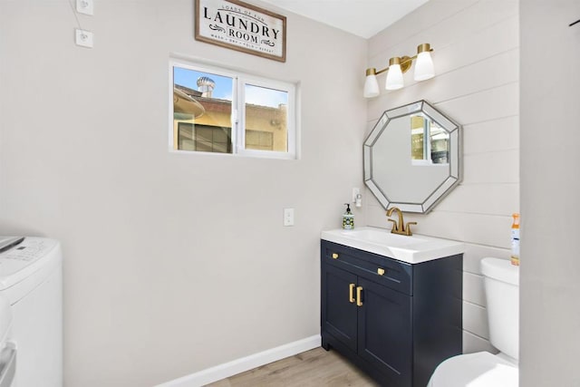 bathroom featuring hardwood / wood-style flooring, vanity, toilet, and washing machine and dryer