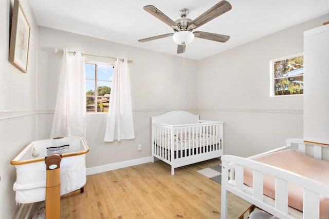 bedroom featuring ceiling fan, light hardwood / wood-style flooring, and a crib