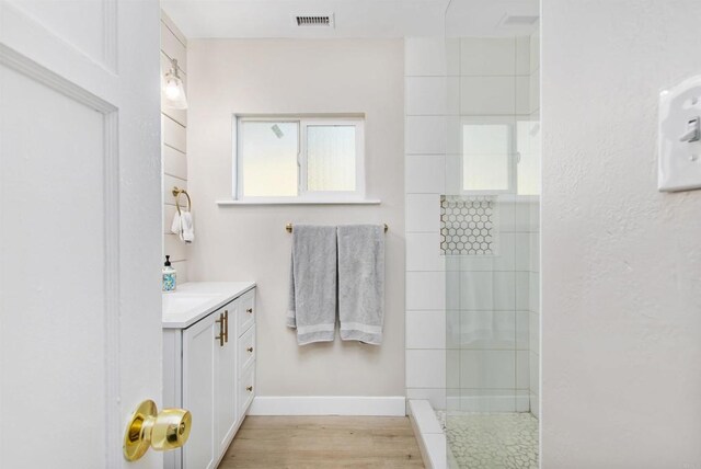 bathroom with tiled shower, wood-type flooring, and vanity