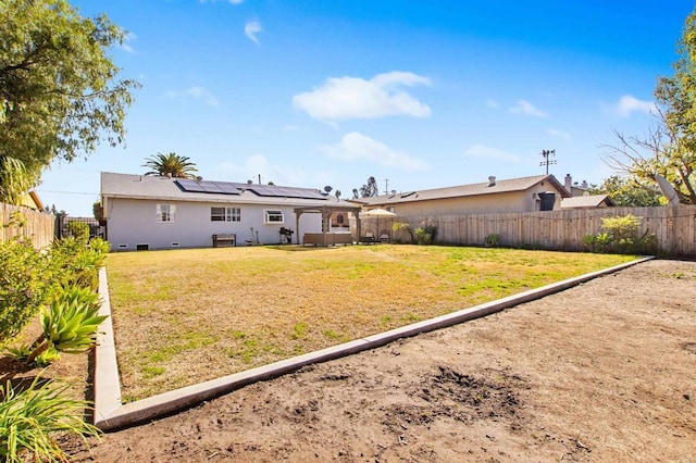 back of house featuring a lawn and solar panels