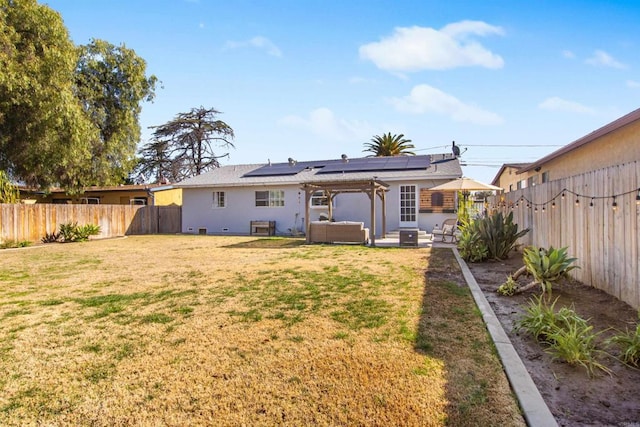 back of property with a patio, an outdoor hangout area, a yard, and solar panels