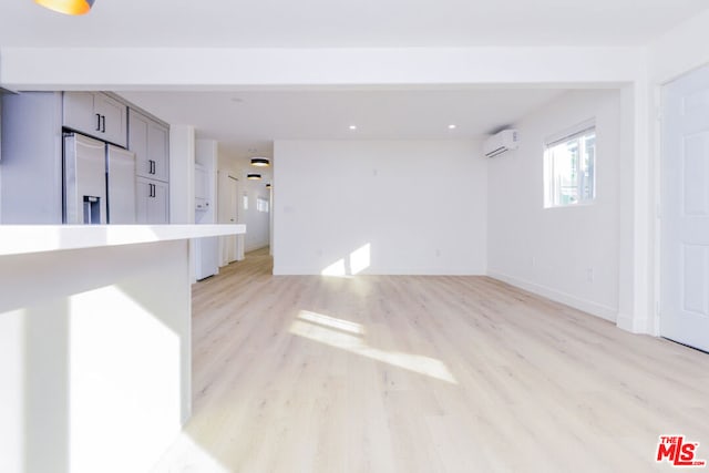 unfurnished living room featuring light hardwood / wood-style flooring and a wall unit AC