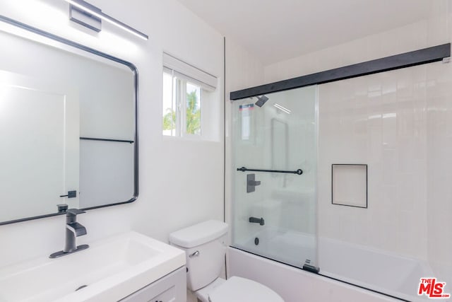 full bathroom with vanity, bath / shower combo with glass door, and toilet