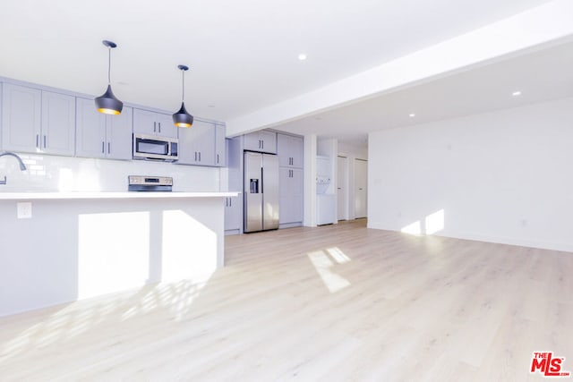 kitchen with gray cabinets, appliances with stainless steel finishes, tasteful backsplash, light hardwood / wood-style floors, and kitchen peninsula