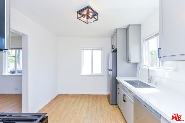 kitchen with sink, stainless steel fridge, dishwasher, a healthy amount of sunlight, and light wood-type flooring