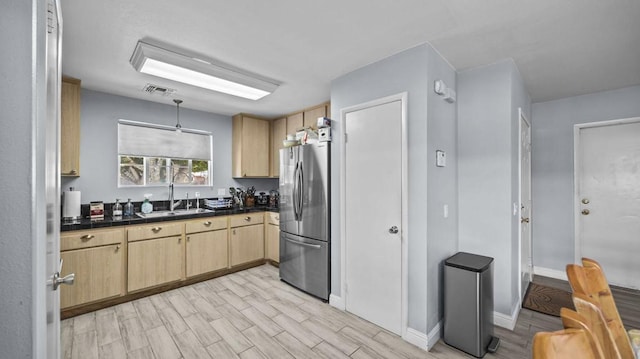 kitchen featuring sink, light brown cabinets, stainless steel refrigerator, and light hardwood / wood-style floors