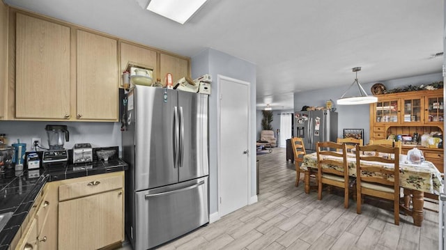 kitchen with stainless steel refrigerator, tile counters, and light brown cabinetry