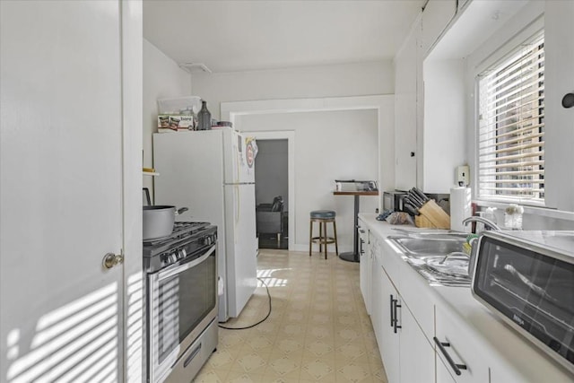 kitchen with white cabinetry, sink, and gas stove