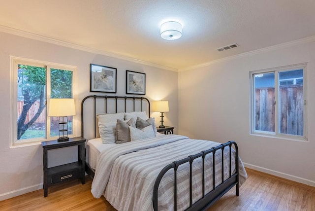 bedroom featuring ornamental molding, light hardwood / wood-style floors, and multiple windows