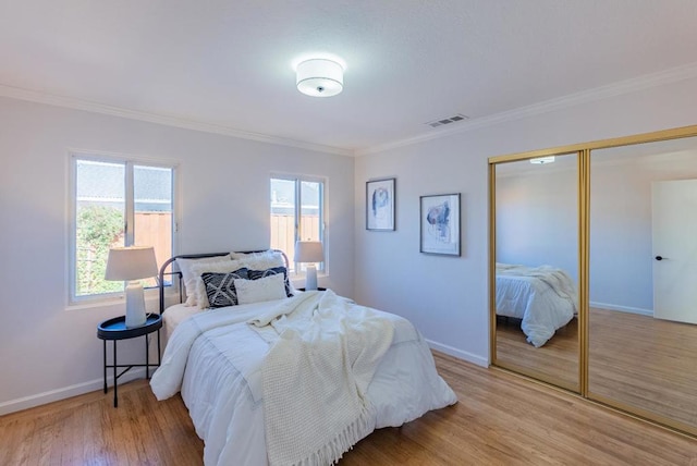 bedroom featuring ornamental molding, light hardwood / wood-style floors, and a closet