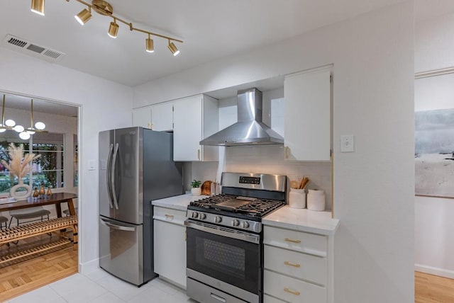 kitchen with appliances with stainless steel finishes, wall chimney range hood, white cabinets, and decorative backsplash