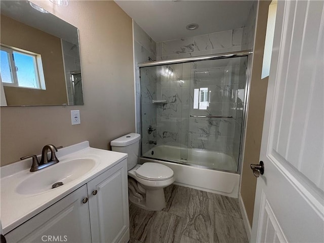 full bathroom featuring vanity, bath / shower combo with glass door, and toilet