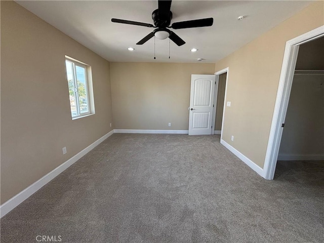 unfurnished bedroom featuring ceiling fan, a spacious closet, a closet, and carpet