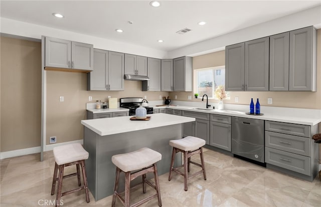 kitchen with gray cabinets, visible vents, appliances with stainless steel finishes, under cabinet range hood, and a kitchen bar