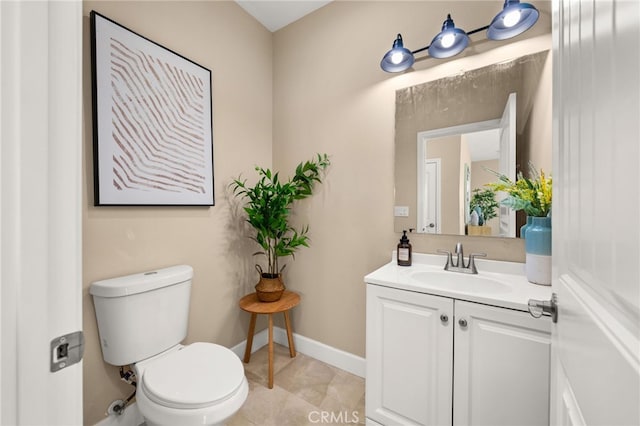 half bath with toilet, baseboards, and vanity