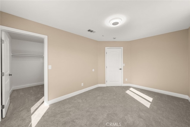 unfurnished bedroom featuring a closet, visible vents, a spacious closet, carpet flooring, and baseboards