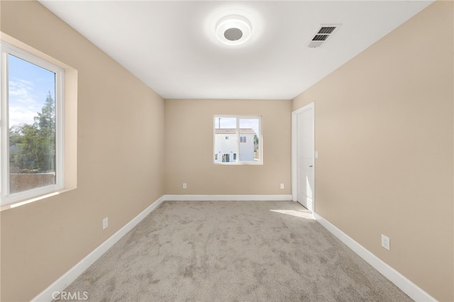 unfurnished room featuring carpet flooring, visible vents, and baseboards