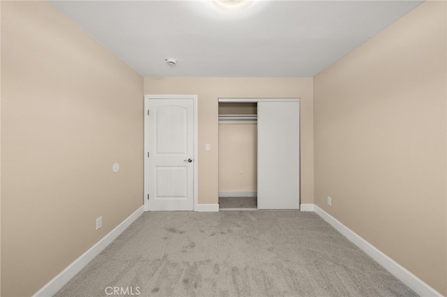 unfurnished bedroom with a closet, carpet, and baseboards