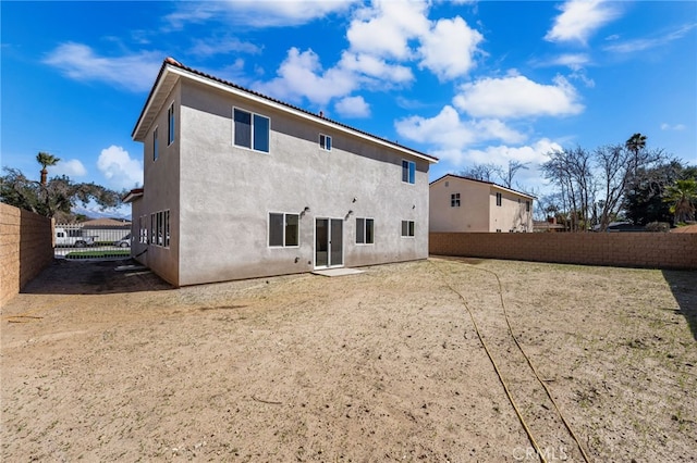 rear view of house with a fenced backyard and stucco siding