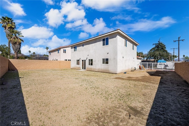 back of house with a fenced backyard and stucco siding