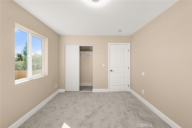 unfurnished bedroom featuring a closet, light carpet, and baseboards