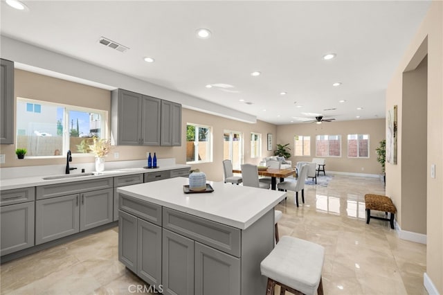 kitchen featuring visible vents, light countertops, a sink, and gray cabinetry