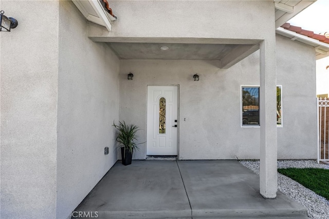 entrance to property with a tile roof and stucco siding