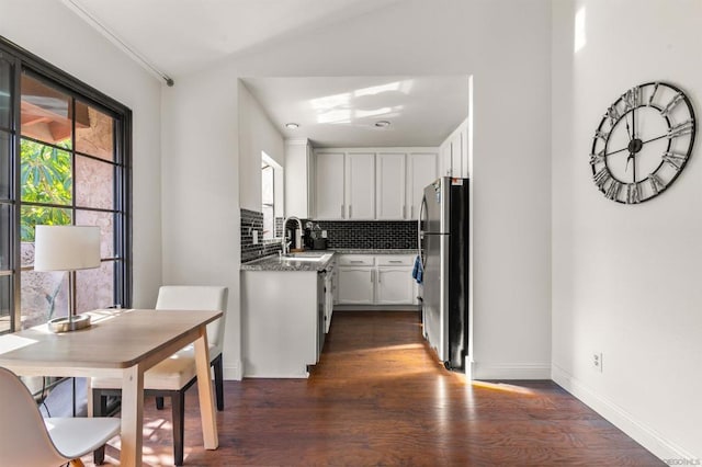 kitchen with sink, appliances with stainless steel finishes, white cabinetry, dark hardwood / wood-style floors, and decorative backsplash