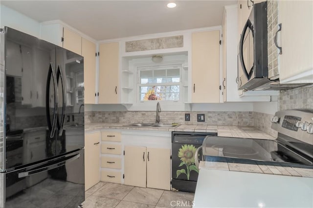 kitchen featuring tasteful backsplash, sink, light tile patterned floors, and black appliances