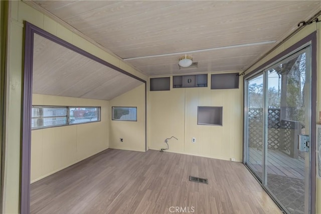 unfurnished room with lofted ceiling with beams, a wealth of natural light, wooden ceiling, and light wood-type flooring