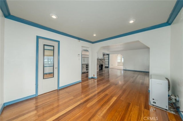 unfurnished living room featuring crown molding, wood-type flooring, and heating unit