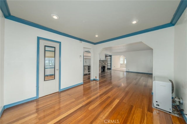 unfurnished living room featuring heating unit, crown molding, and hardwood / wood-style floors