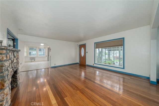 unfurnished living room featuring a stone fireplace and light hardwood / wood-style floors